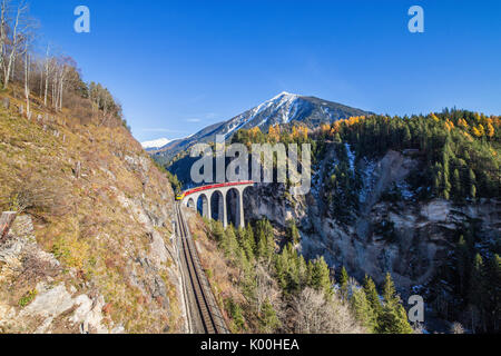 Bernina Express passes through Landwasser Viadukt surrounded by colorful woods Canton of Graubünden Switzerland Europe Stock Photo