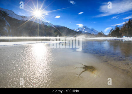 Winter sun light up the frozen Lake Silvaplana surrounded by mist Maloja Canton of Graubünden Engadine Switzerland Europe Stock Photo