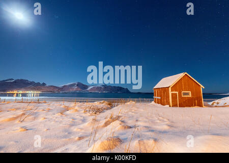 Moonlight on a typical fishermen cabin surrounded by snow Ramberg Flakstad Nordland County Lofoten Norway Europe Stock Photo