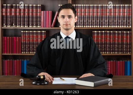 Portrait of confident judge against bookshelf in courtroom Stock Photo