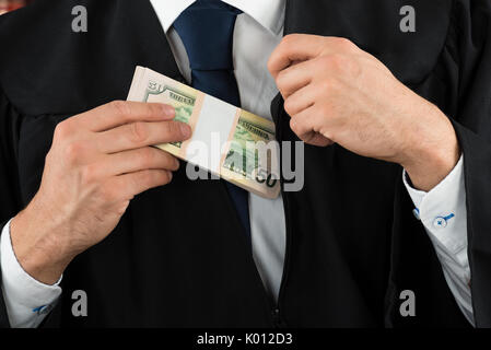 Closeup midsection of corrupt judge putting dollar bundle in pocket Stock Photo