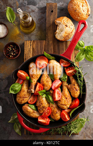 Roasted chicken drumsticks in a cast iron pan Stock Photo