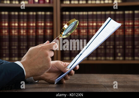 Cropped image of lawyer examining documents with magnifying glass in courtroom Stock Photo