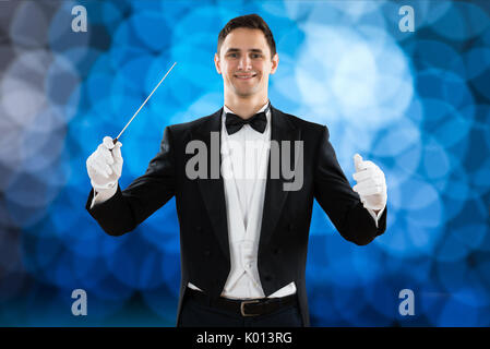 Portrait of happy music conductor holding baton against colored background Stock Photo