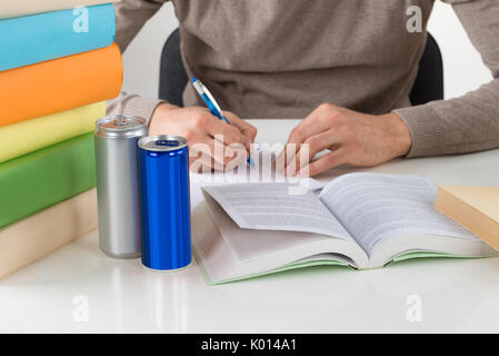 Midsection of male student writing in book while studying at table Stock Photo