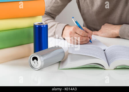 Midsection of male student writing in book while studying at table Stock Photo