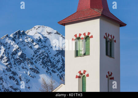 Bell tower of the alpine church framed by snowy peaks Maloja Bregaglia Valley Canton of Graubünden Engadine Switzerland Europe Stock Photo