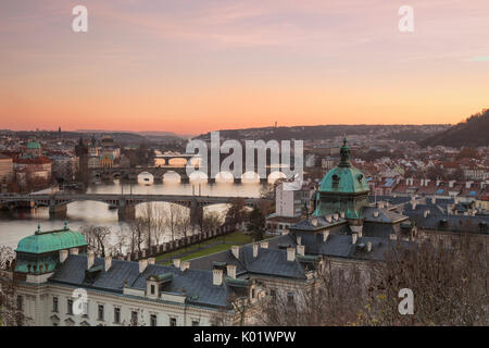 Pink sky on historical bridges and buildings reflected on Vltava (Moldava) river at sunset Prague Czech Republic Europe