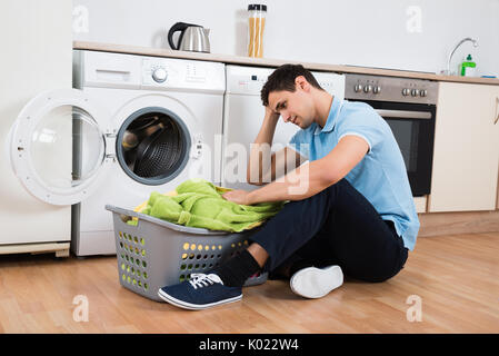 Tensed young man looking at laundry basket at home Stock Photo