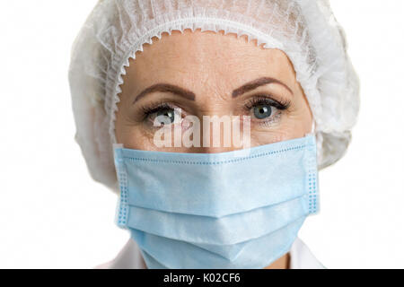 Detail of female mature doctor. Female white-skin doctor close up wearing mask, white background. Medical and healthcare concept. Stock Photo