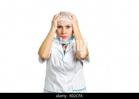 Female doctor shocked with hands on head. Close up portrait of a shocked female doctor or nurse wearing a mask and looking worried on white background Stock Photo