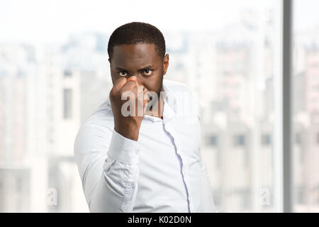 Serious man holding out his fist. Black man in white shirt shake his fist. Concept of power and authority. Stock Photo