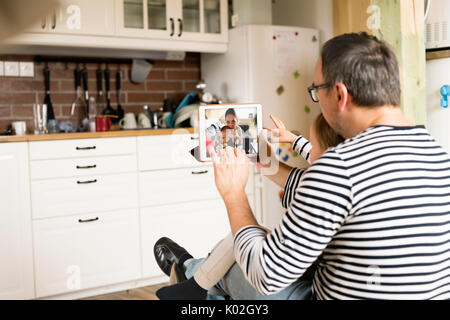 Young father videochatting with mother on tablet. Stock Photo