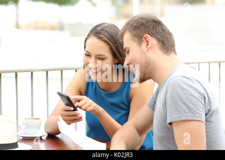 Portrait of a happy couple of tourists planning travel sitting in a coffee shop Stock Photo