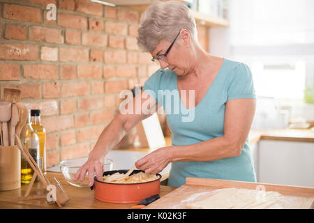 Pensive grandmother baking delicious apple pie Stock Photo