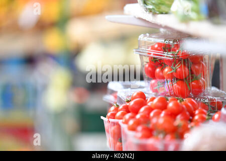 Fresh cherry tomatoes in plastic box at market place Stock Photo
