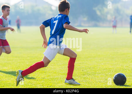 Boy kicking soccer ball on sports field Stock Photo