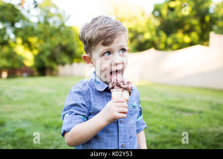 Preschool boy eating ice cream cone in summer yard Stock Photo