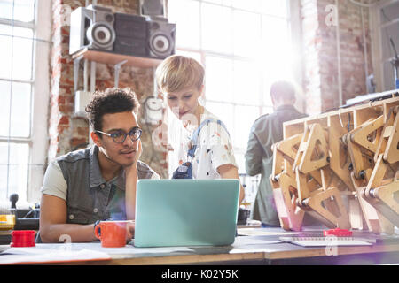 Serious, focused designers working at laptop in workshop Stock Photo