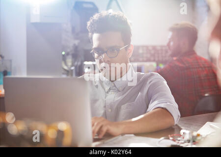 Serious, focused young male designer working at laptop in workshop Stock Photo