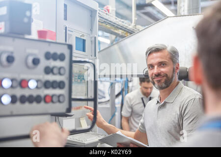 Portrait smiling male manager at machinery control panel in factory Stock Photo