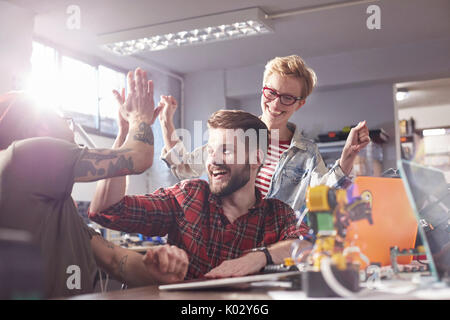 Enthusiastic designers high-fiving, celebrating in workshop Stock Photo