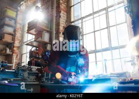 Welder welding with welding mask and torch in workshop Stock Photo