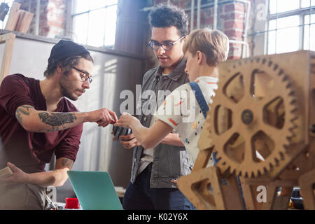 Designers examining and discussing prototype in workshop Stock Photo