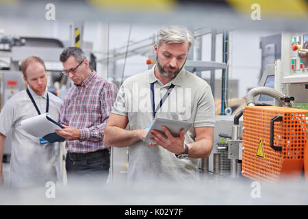 Male supervisor using digital tablet in fiber optics factory Stock Photo
