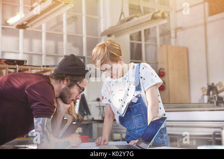 Designers reviewing plans at laptop in workshop Stock Photo