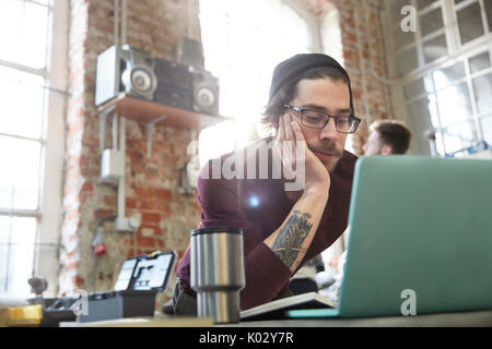 Young male designer using laptop in workshop Stock Photo