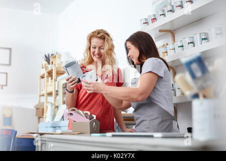 Smiling female business owner helping customer choose paint in art shop Stock Photo