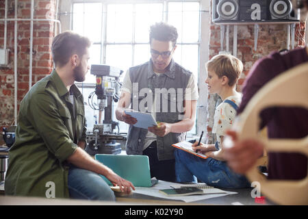 Designers meeting, using clipboard and laptop in workshop Stock Photo
