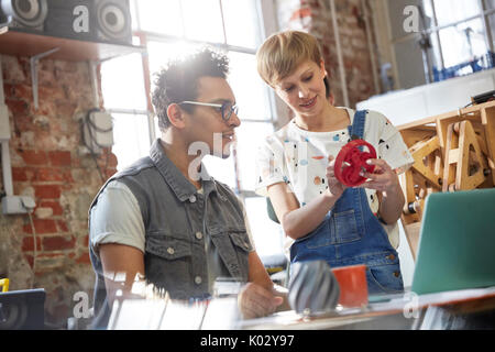 Designers discussing prototype cog in workshop Stock Photo