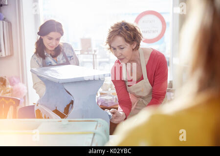 Female artists painting wooden bench blue in art class workshop Stock Photo