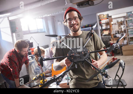 Portrait smiling male designer holding drone in workshop Stock Photo