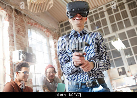 Smiling female computer programmer testing virtual reality simulator glasses and joystick Stock Photo
