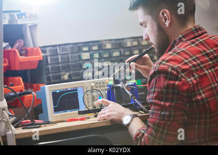 Male engineer assembling electronics, using soldering iron Stock Photo