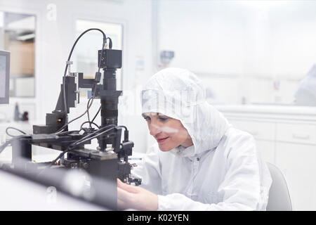Female engineer in clean suit using equipment in fiber optics research and testing laboratory Stock Photo