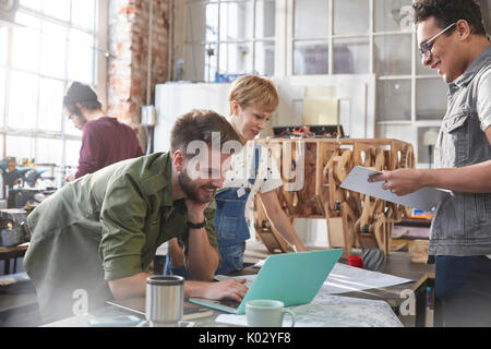 Designers brainstorming at laptop in workshop Stock Photo