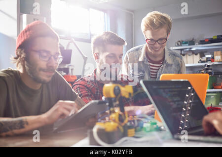 Computer programmers using laptops and digital tablet, programming robotics in workshop Stock Photo