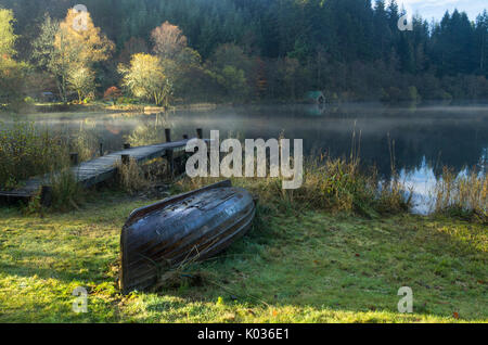 Up turned rowing boat on a misty morning with reflection, Loch Ard, Scotland Stock Photo