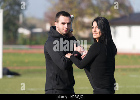 Young Couple Stretching Before Running In City Park Area - Training And Exercising For Trail Run Marathon Endurance - Fitness Healthy Lifestyle Concep Stock Photo