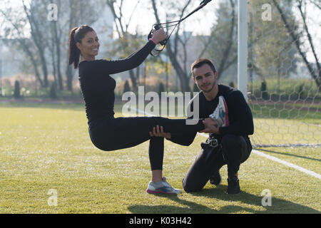 Young Couple Doing Crossfit With Trx Fitness Straps in City Park Area - Training and Exercising for Endurance - Healthy Lifestyle Concept Outdoor Stock Photo