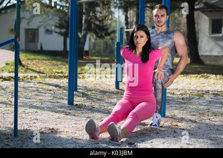 Young Couple Doing Crossfit Exercise With Dips Bar in City Park Area - Training and Exercising for Endurance - Healthy Lifestyle Concept Outdoor Stock Photo