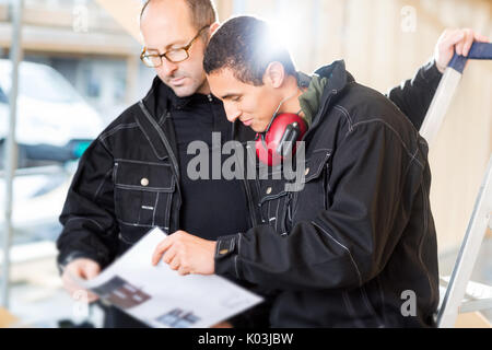Carpenters Looking At Plan While Standing At Site Stock Photo