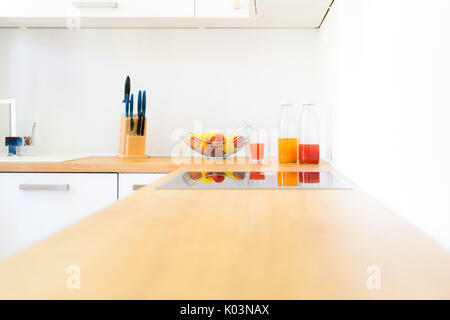 Modern wooden kitchen counter with induction hob, fresh fruit and homemade lemonade Stock Photo