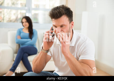 Wife With Curiosity Looking At Husband Talking Privately On Cellphone Stock Photo