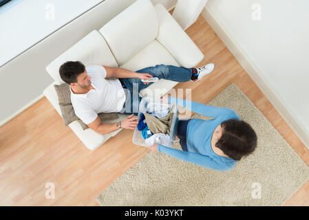 High Angle View Of A Woman Giving Laundry Basket To Man Holding Remote Control Stock Photo