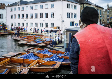 Big Issue Seller looks out over punts on the River Cam in Cambridge UK Stock Photo
